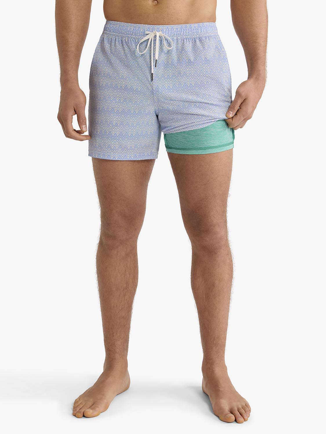 Man wearing light blue textured swim trunk with green underlay and drawstring waistband.