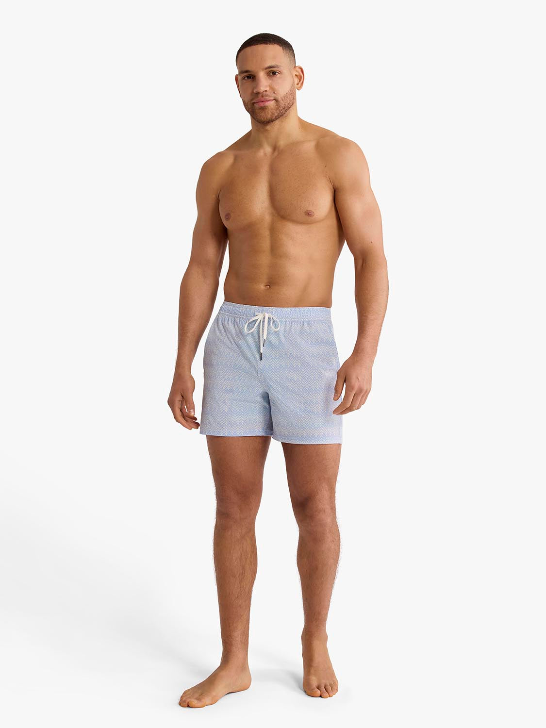 Man wearing light blue textured swim shorts with drawstring waistband standing against white background.