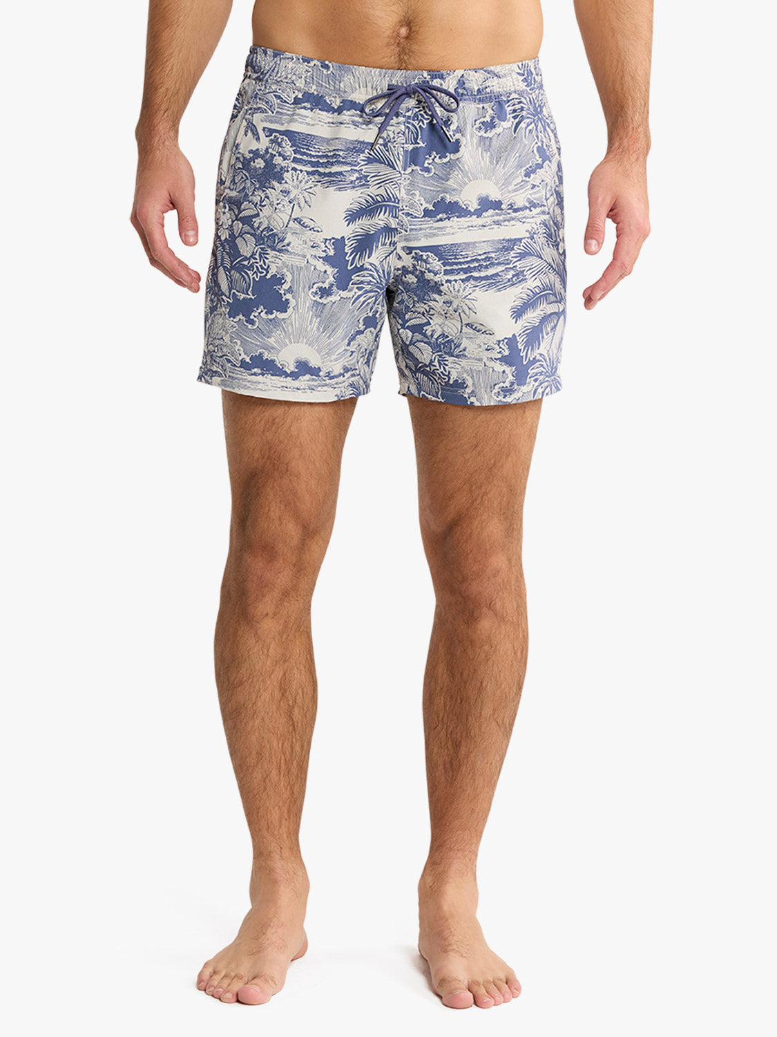 Man wearing blue and cream palm print swim trunks with drawstring waistband standing barefoot.