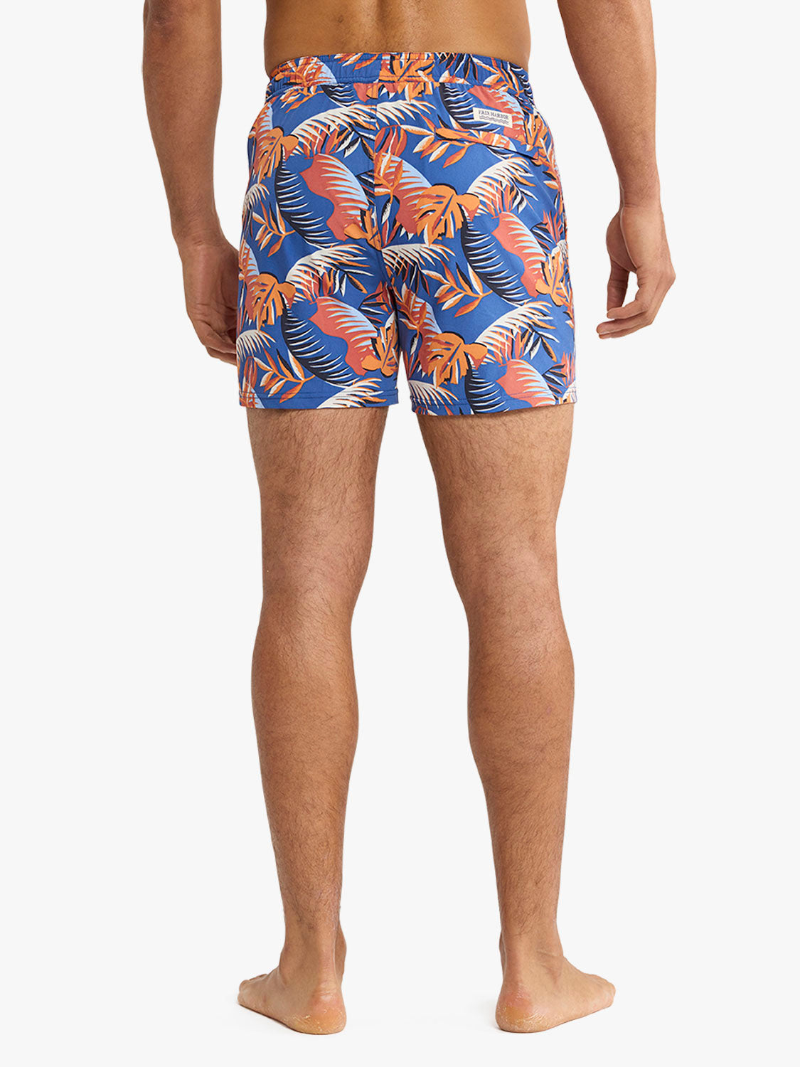 Man wearing blue swim trunks with orange and white palm leaf print design.