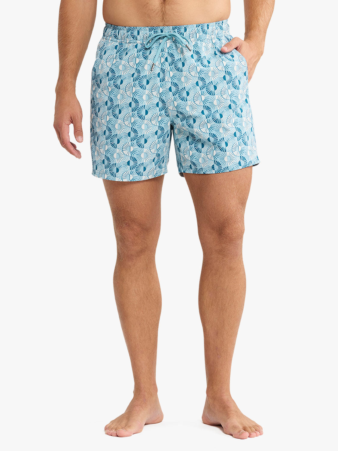 Man wearing light blue swim shorts with an all-over sunburst pattern and drawstring waist.