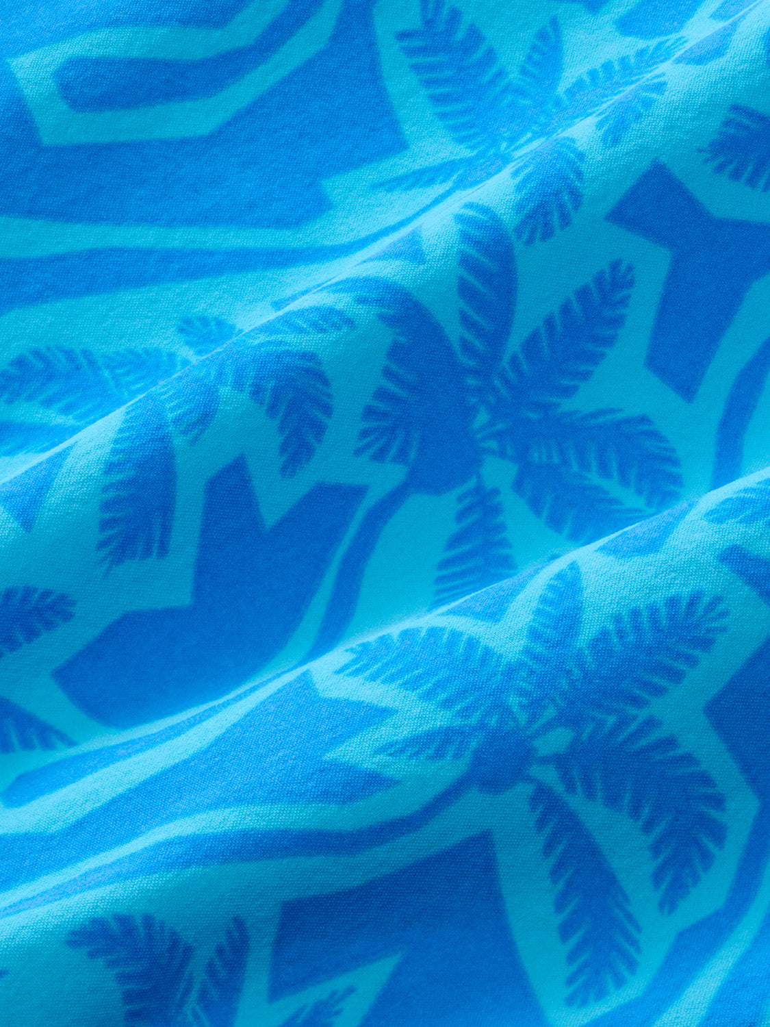Turquoise fabric with darker blue palm leaf cutout patterns and wavy stripes throughout the material.