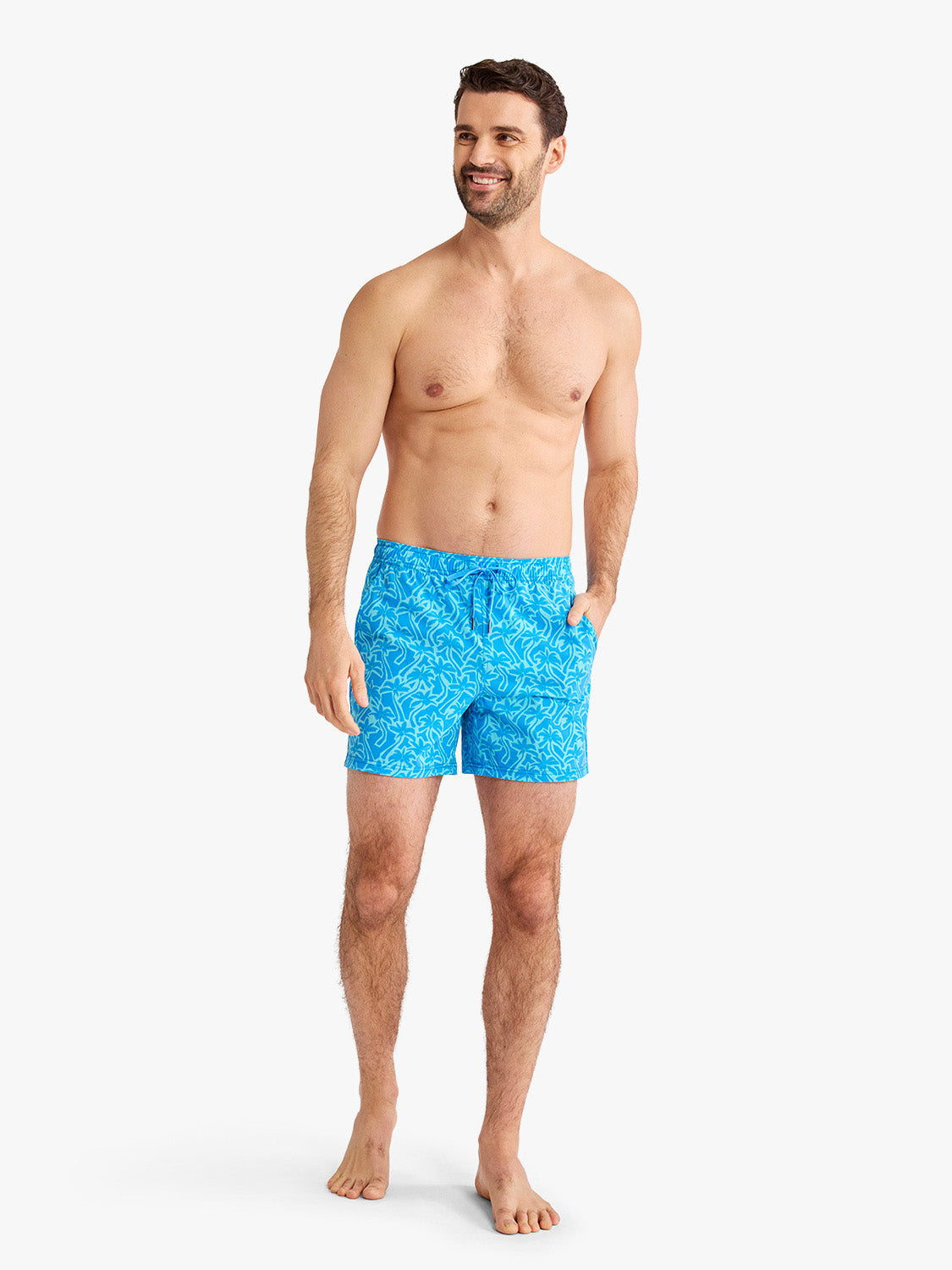 Man wearing turquoise swim shorts with palm leaf cutout pattern and drawstring waist.