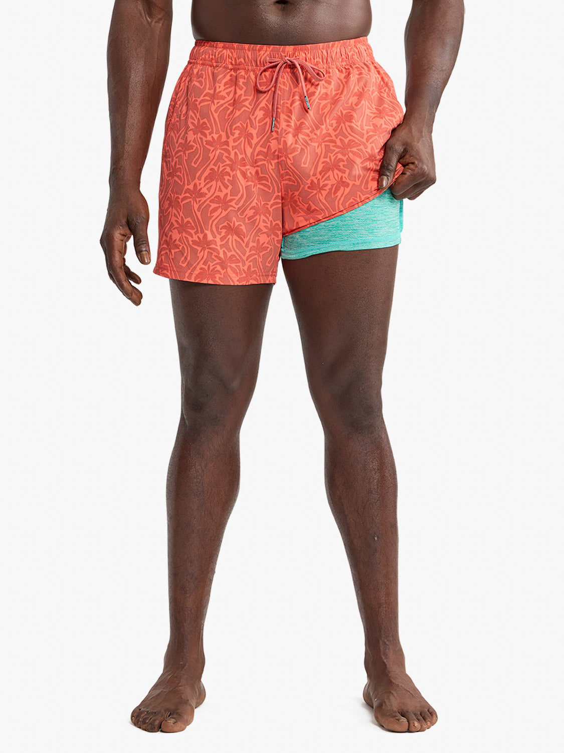 Coral swim trunk with cutout palm leaf pattern and turquoise contrast underlay detail.