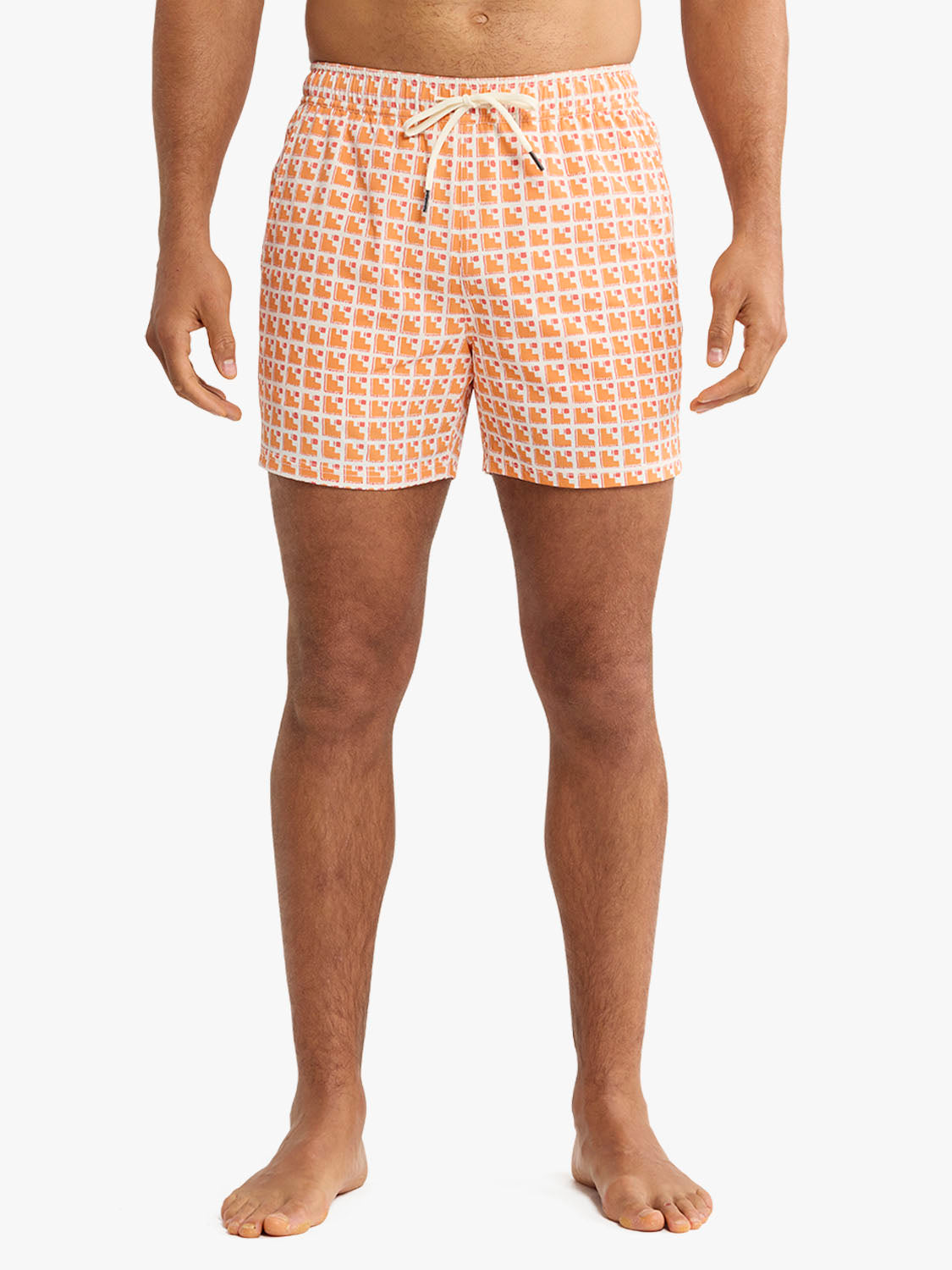 Man wearing orange and white patterned swim trunks with a drawstring waist standing against white background.