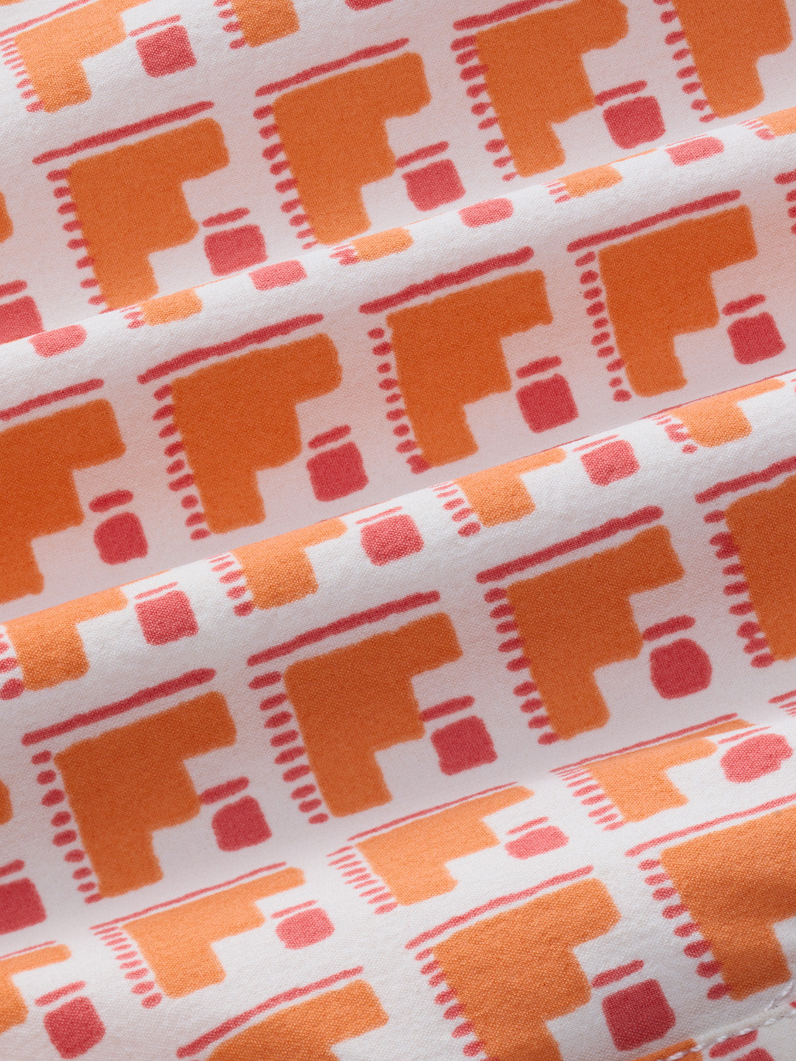 Fabric trunk features a repeating geometric pattern in orange, coral, and cream with stair-step motif designs.
