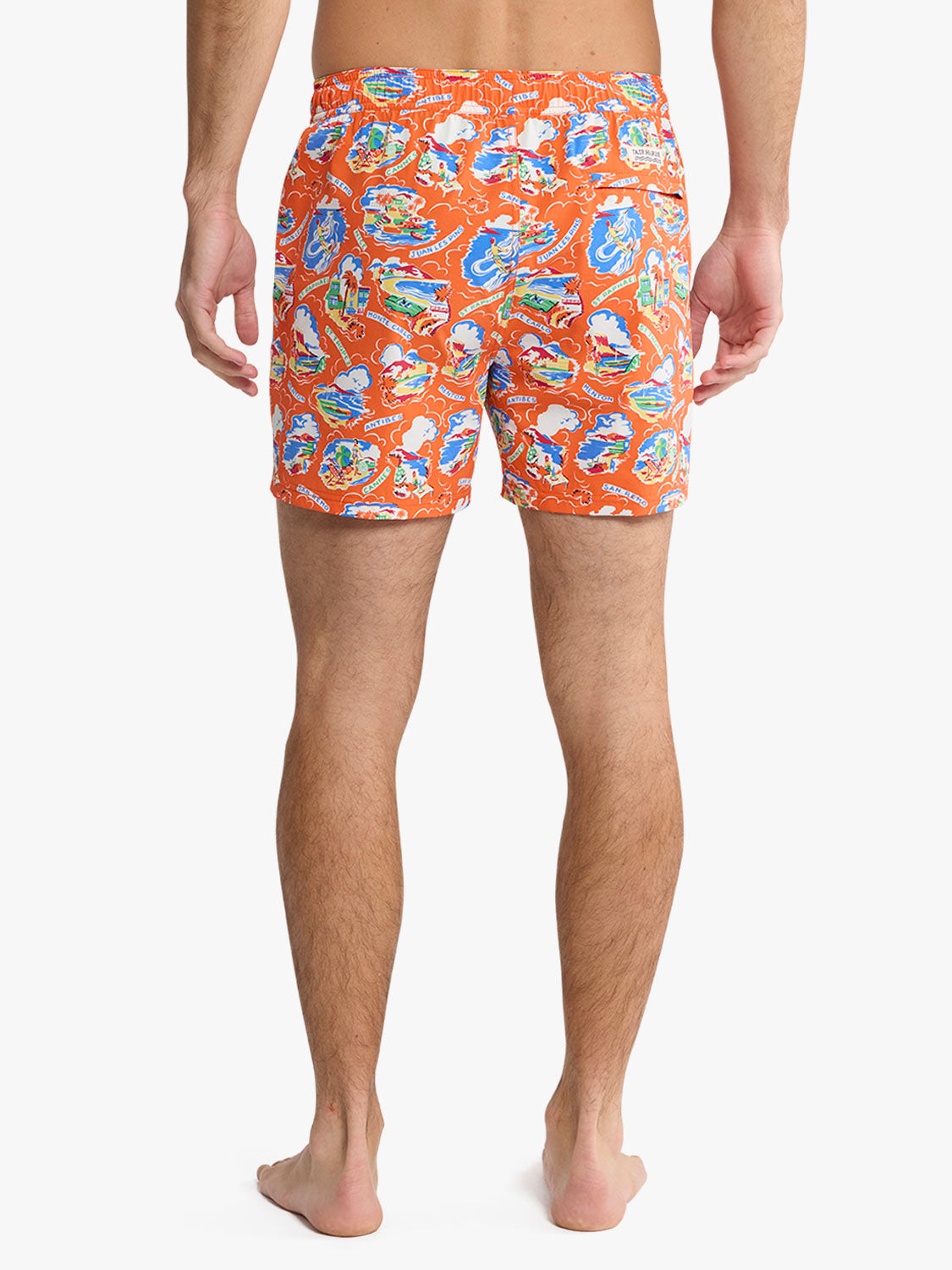 Man wearing red swim trunks with blue and white boat and coastal pattern print.