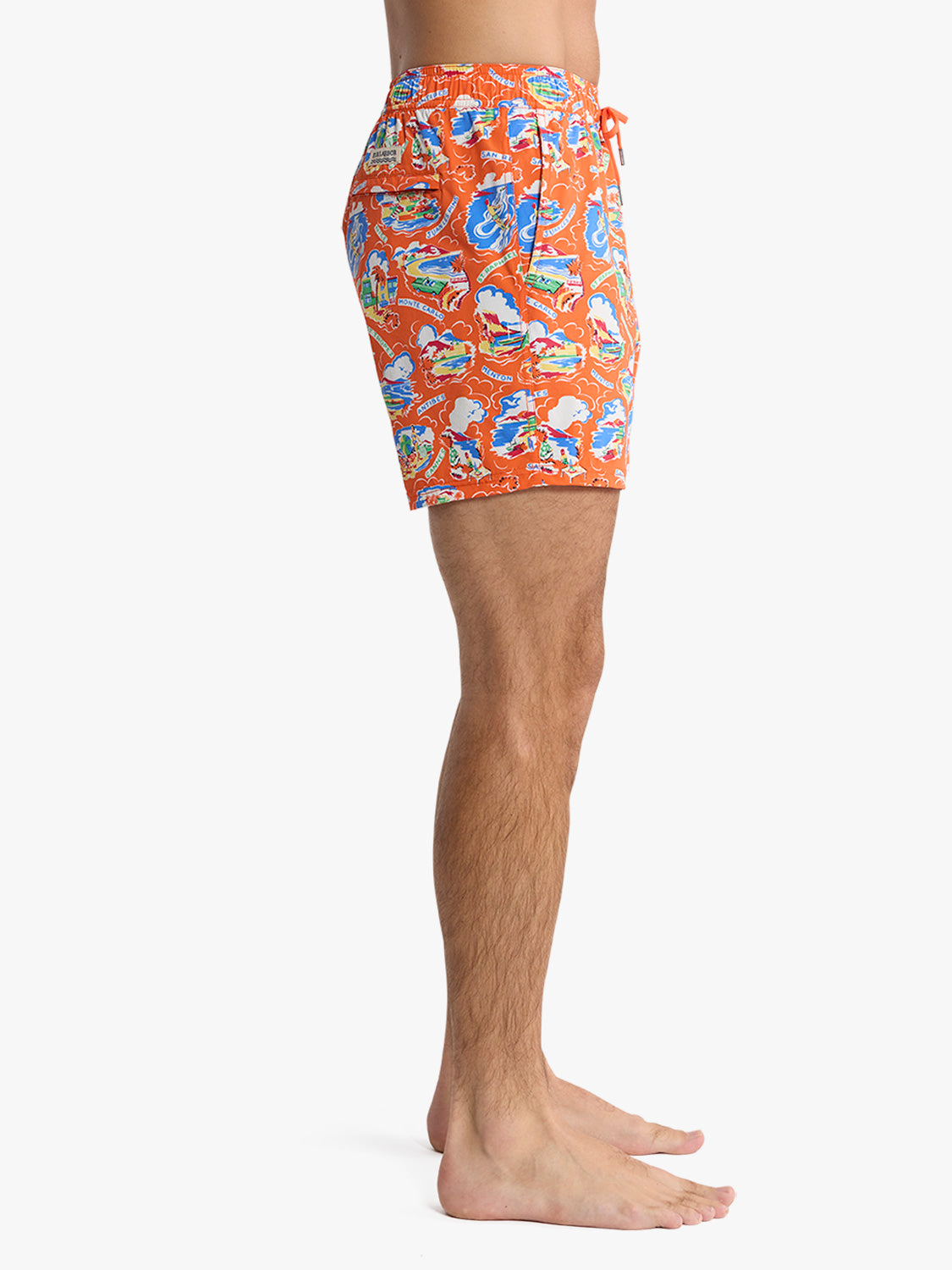 Man wearing orange swim shorts with blue and colorful boat print pattern and drawstring waist.
