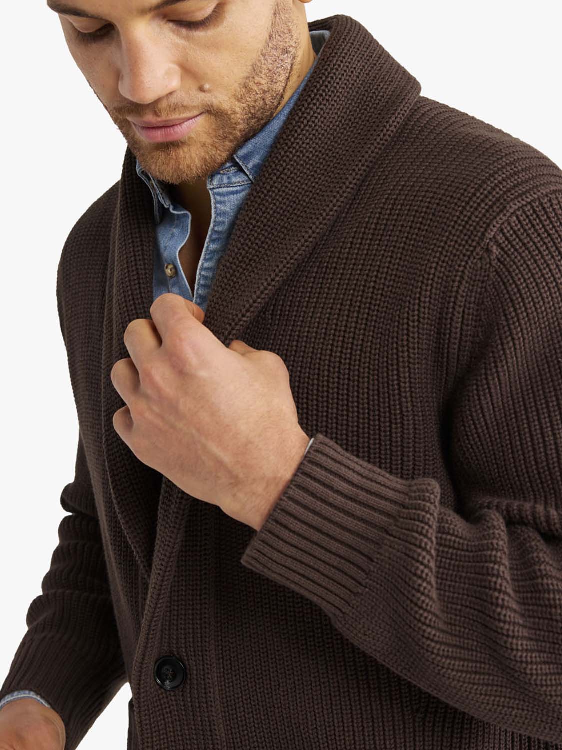 Man wearing a dark brown textured cardigan sweater over a blue denim shirt.