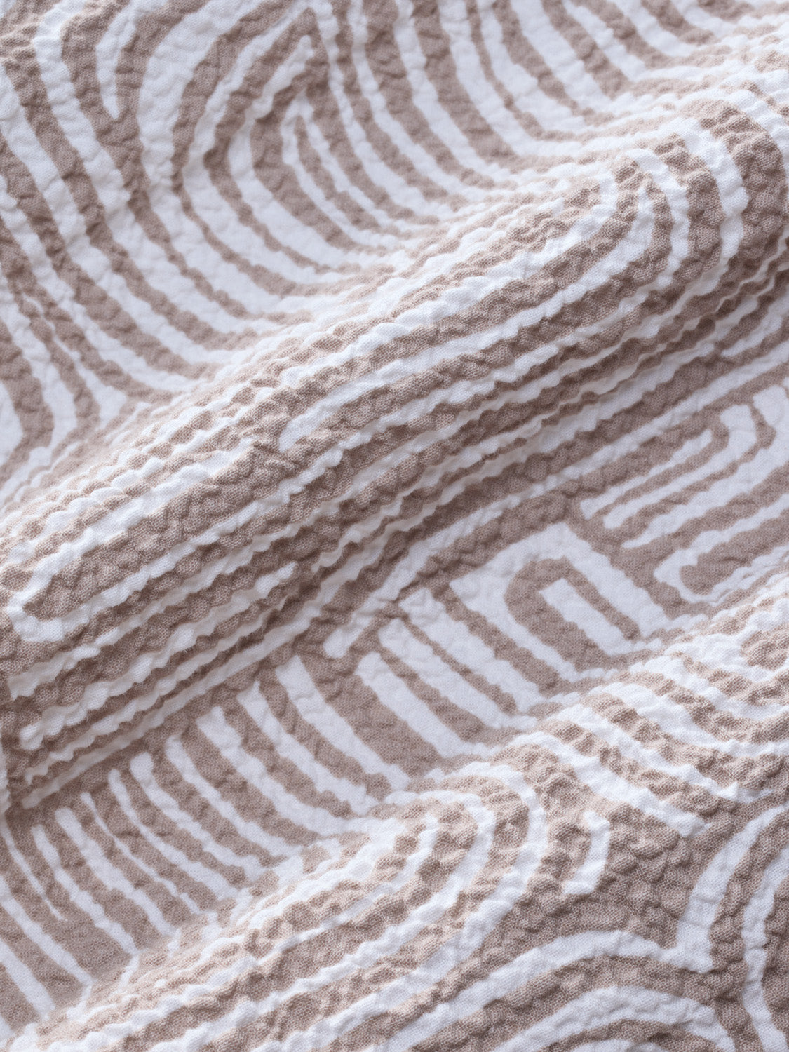 Beige and white textured fabric with wavy striped pattern and quilted surface detail.