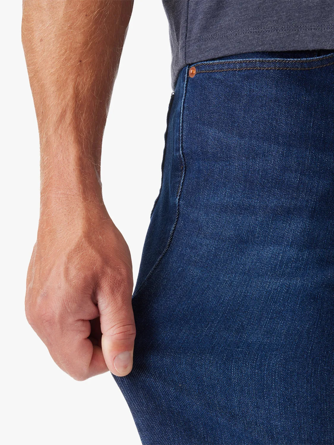 Close up of person wearing driftwood denim in deep sea wash pulling on the side seam of jeans to show the stretch of the jeans. 