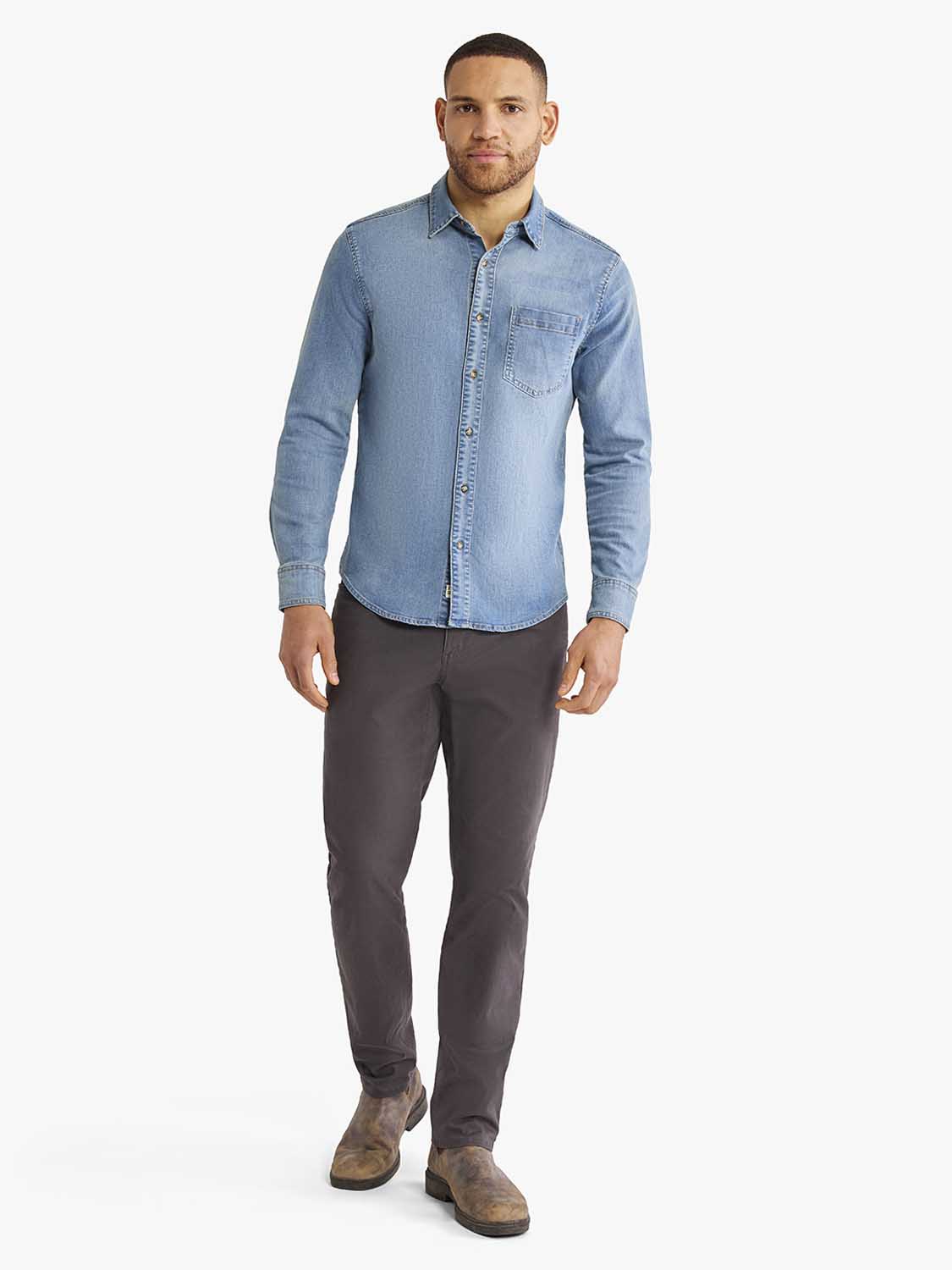 Man wearing a medium wash denim shirt with a chest pocket and dark gray pants.