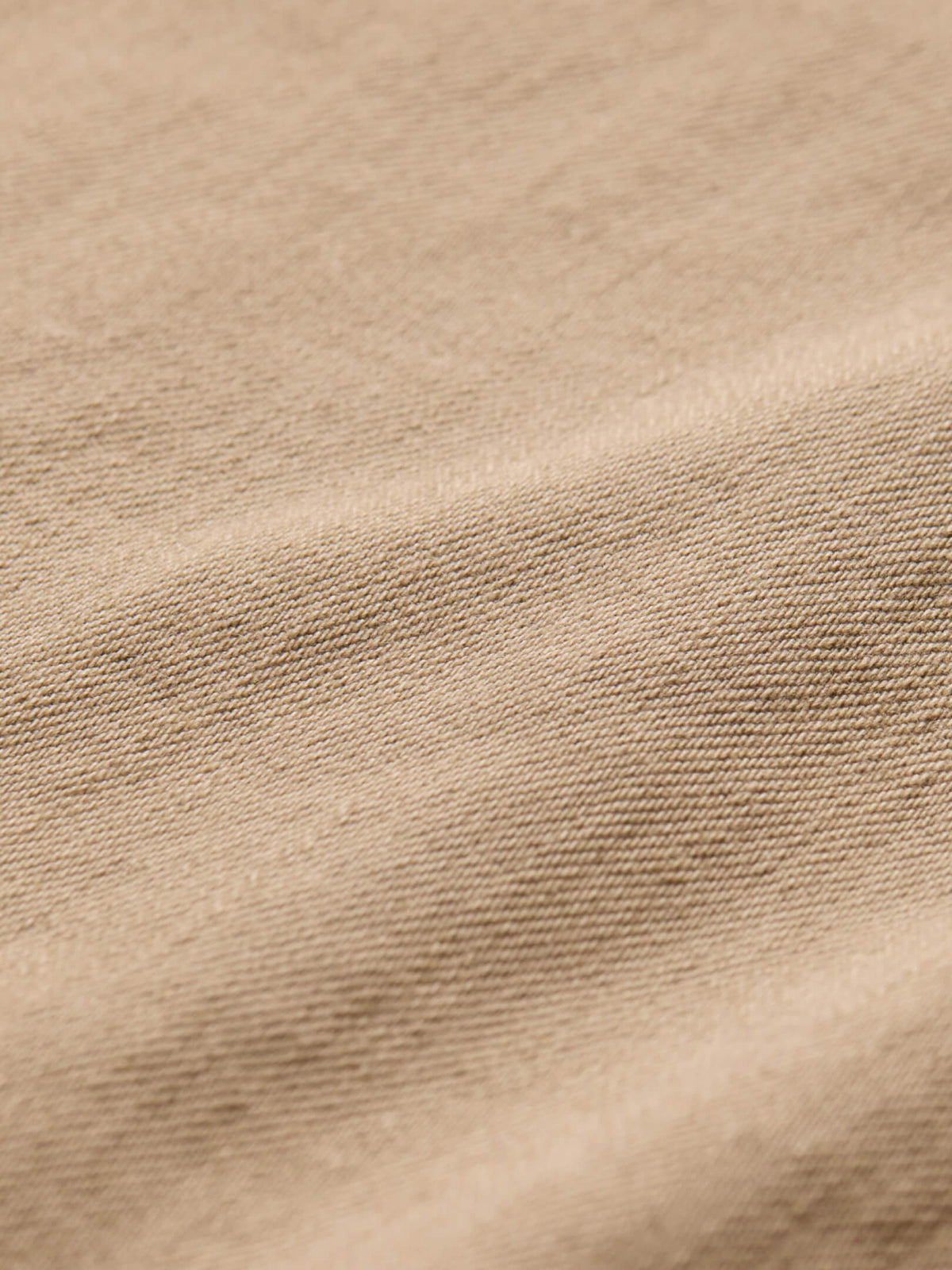 Close-up of khaki denim fabric showing woven texture and neutral beige coloring.