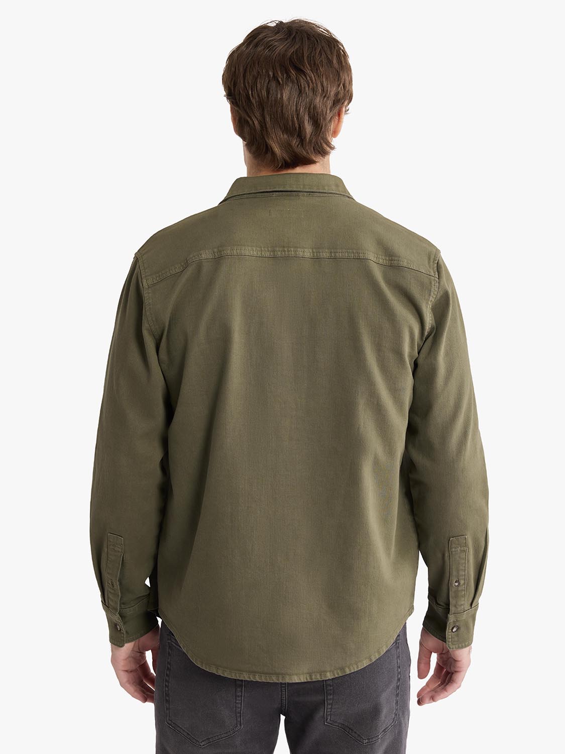 Man wearing an olive-colored denim shirt with long sleeves and button cuffs, viewed from behind.