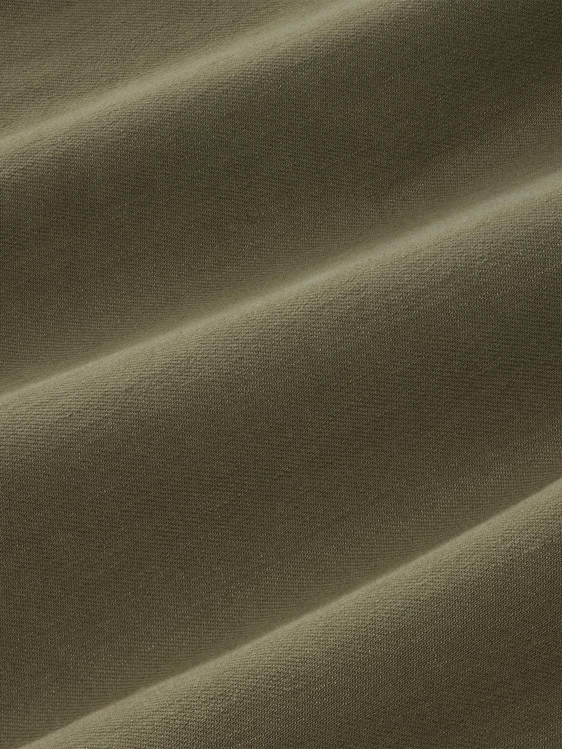 Olive-toned denim fabric with a textured weave and diagonal fold creating shadow highlights.