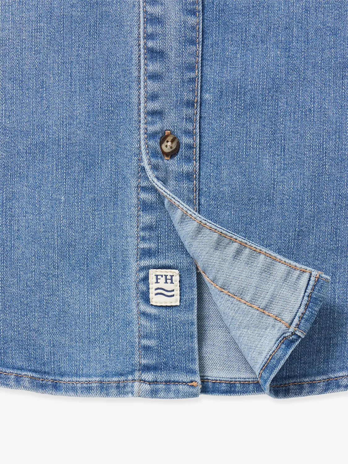 Medium wash denim shirt with mother-of-pearl button and brand label detail visible.