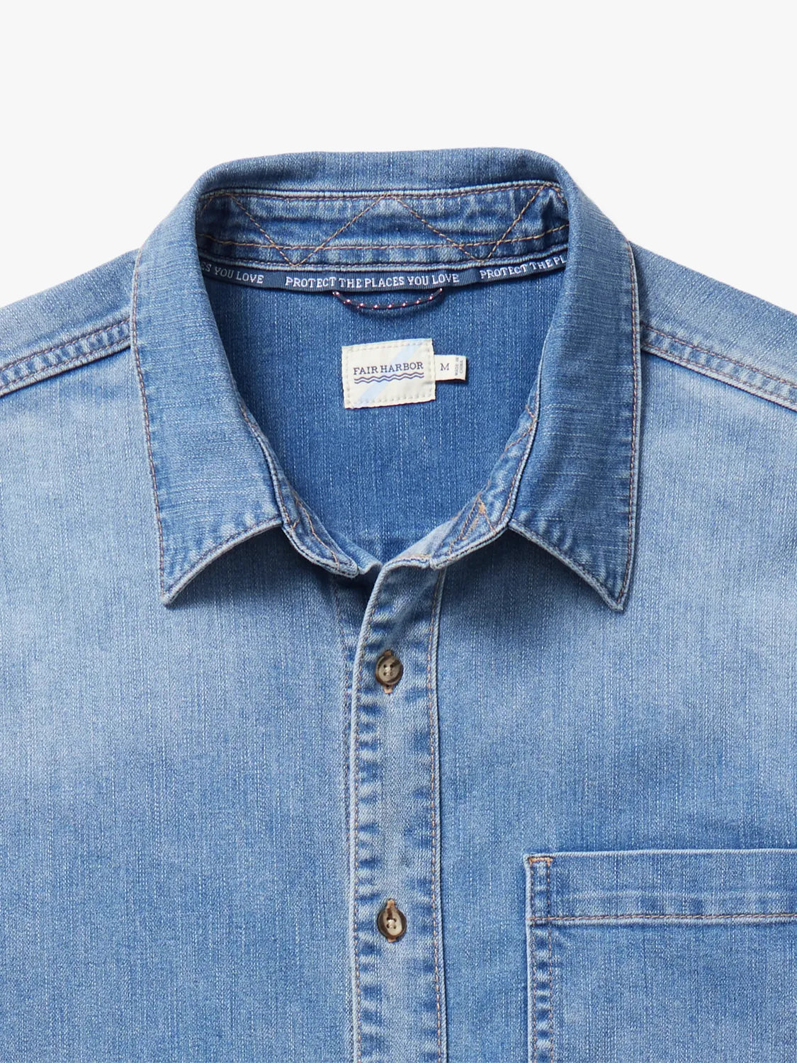 Medium wash denim shirt with collar and front button closure displayed on neutral background.