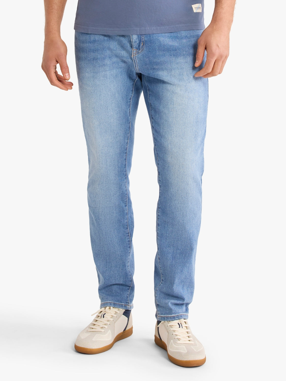 Person wearing light blue jeans from Fair Harbor and white sneakers on a white background