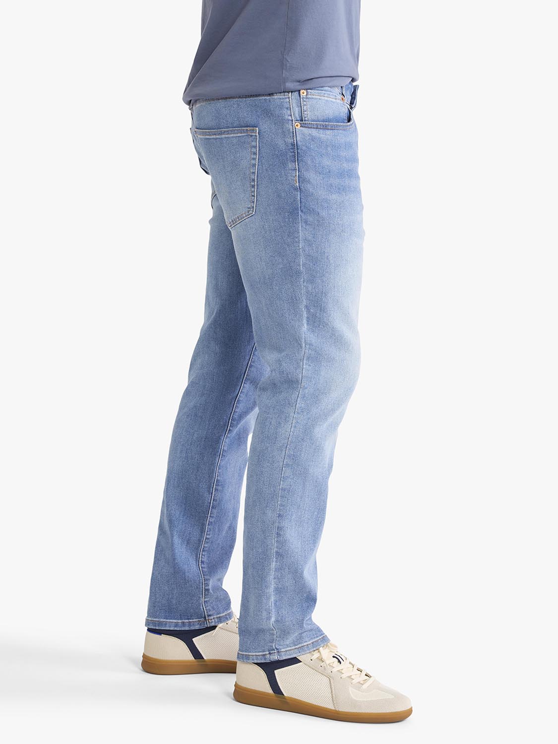 Light blue wash denim pants with a relaxed fit displayed on a model wearing casual sneakers.