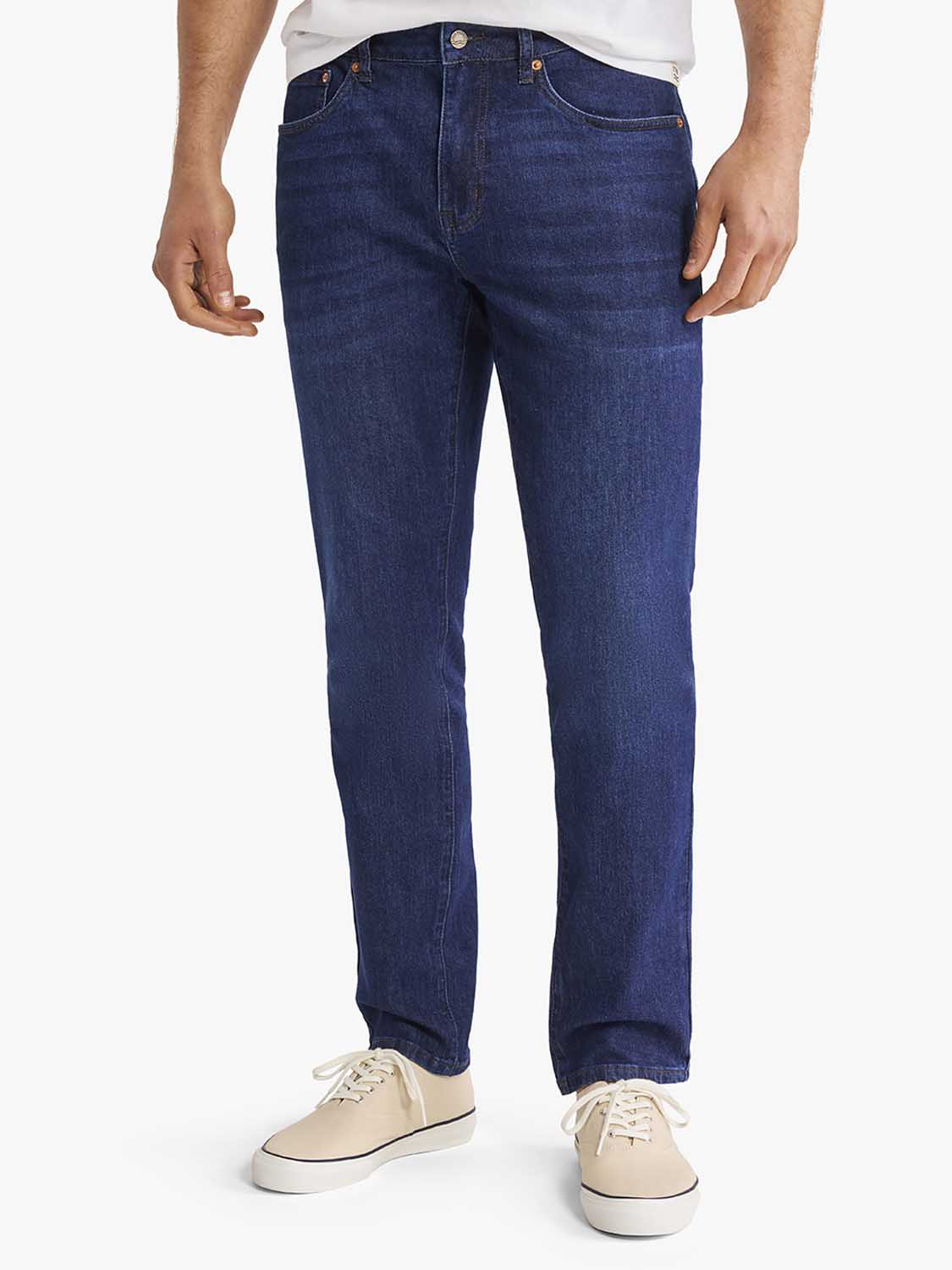 Man wearing deep sea wash denim pants with a white shirt and beige canvas shoes.