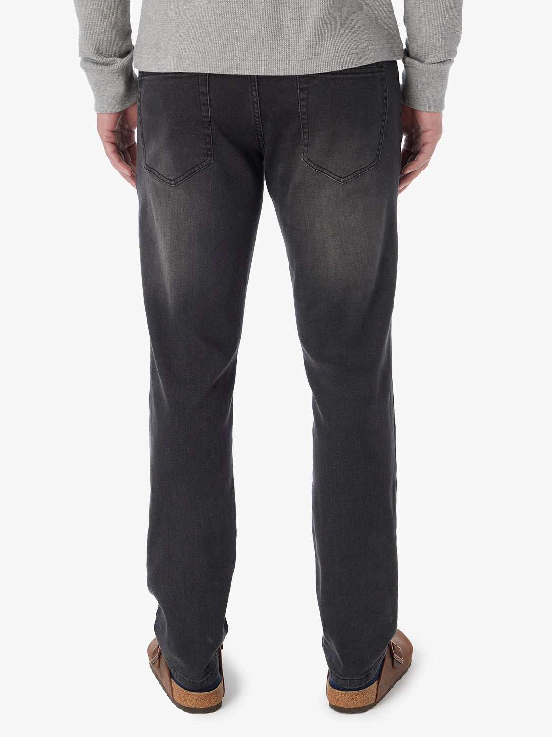 Person wearing black wash denim pants with visible back pockets and a gray sweater.