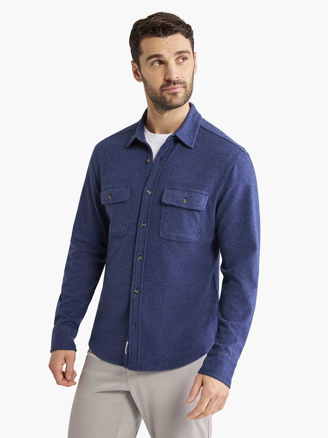 Man wearing a navy blue flannel shirt with chest pockets and button front closure.
