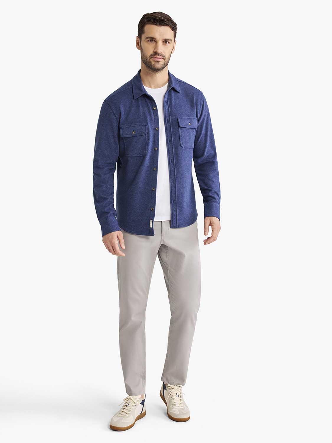 Man wearing a navy blue flannel shirt with chest pockets over a white undershirt and beige pants.