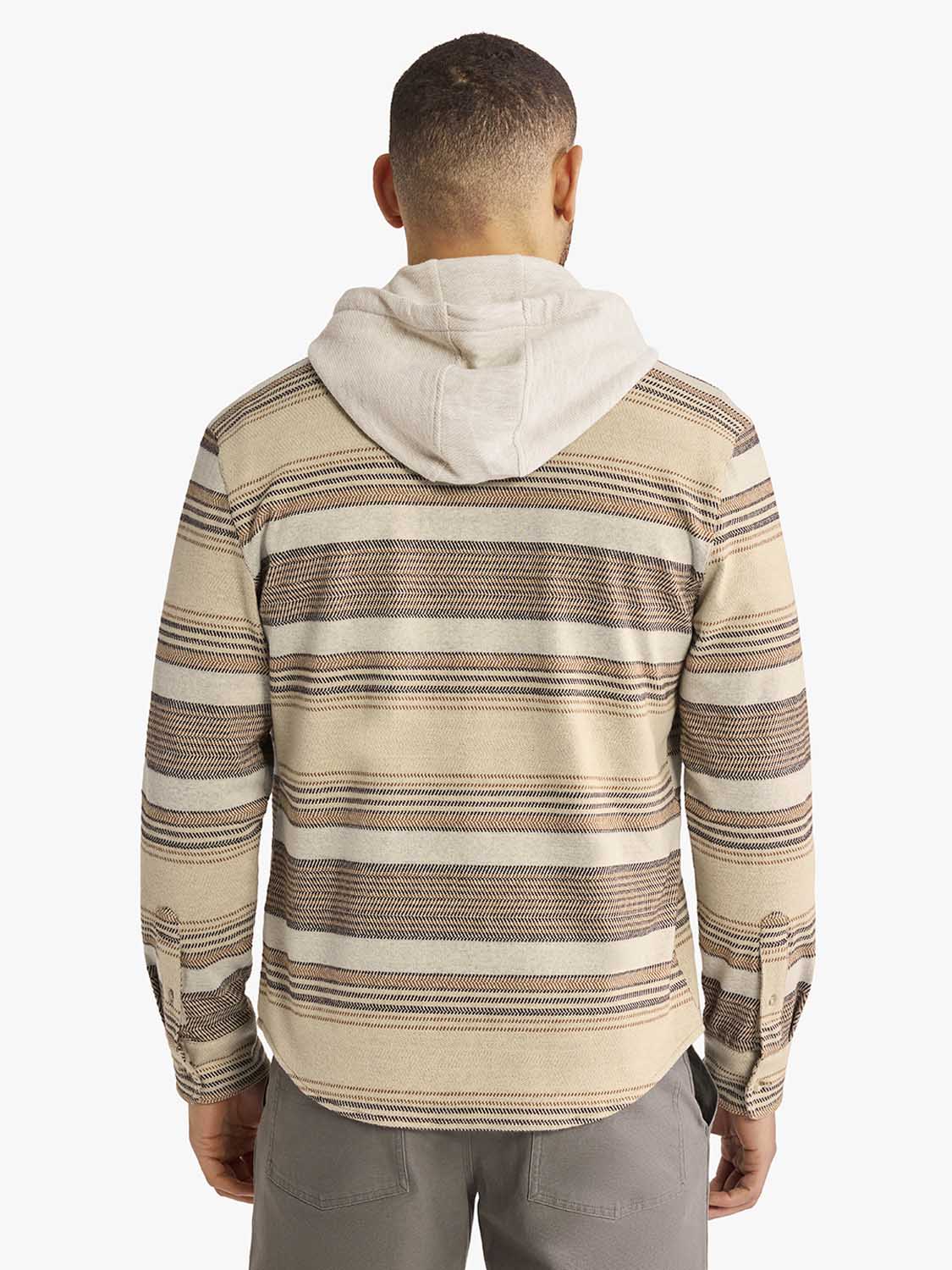 Man wearing a striped flannel shirt with horizontal bands in cream, brown, and tan colors with a cream hood.