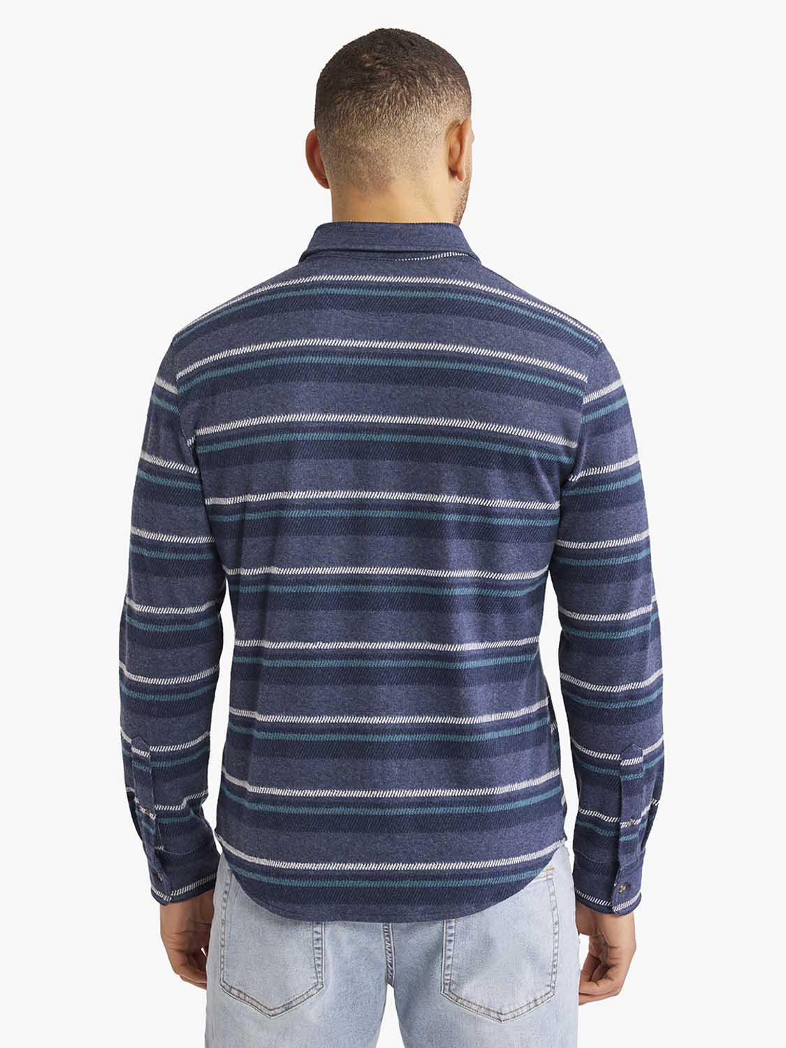 Man wearing a navy flannel shirt with horizontal stripes in teal, white, and purple throughout.
