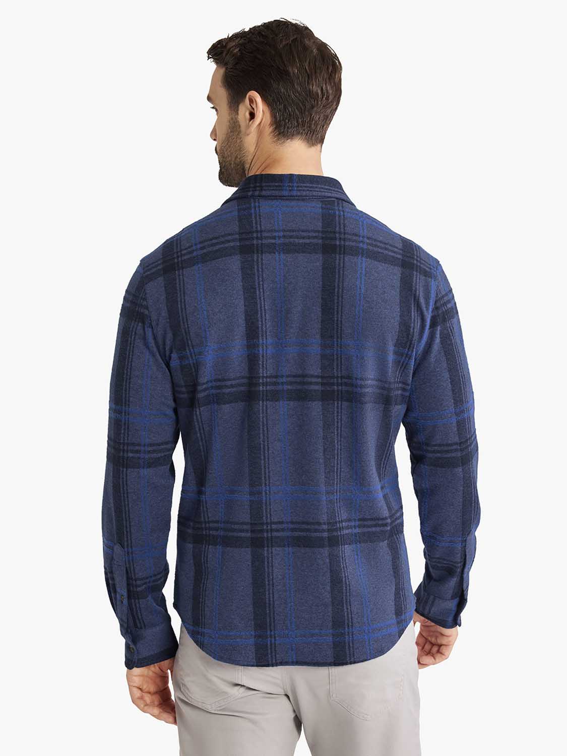 Man wearing a navy blue flannel shirt with a dark plaid pattern, shown from the back view.