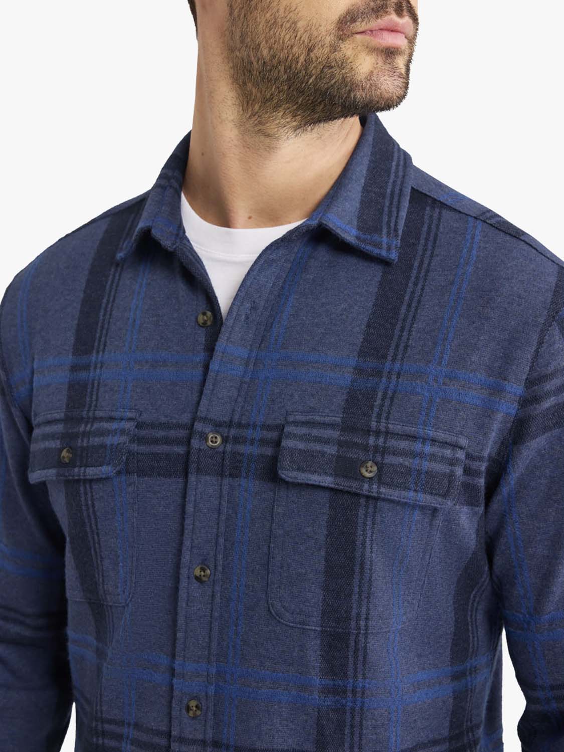 Man wearing a navy plaid flannel shirt with blue and black grid pattern over white undershirt.