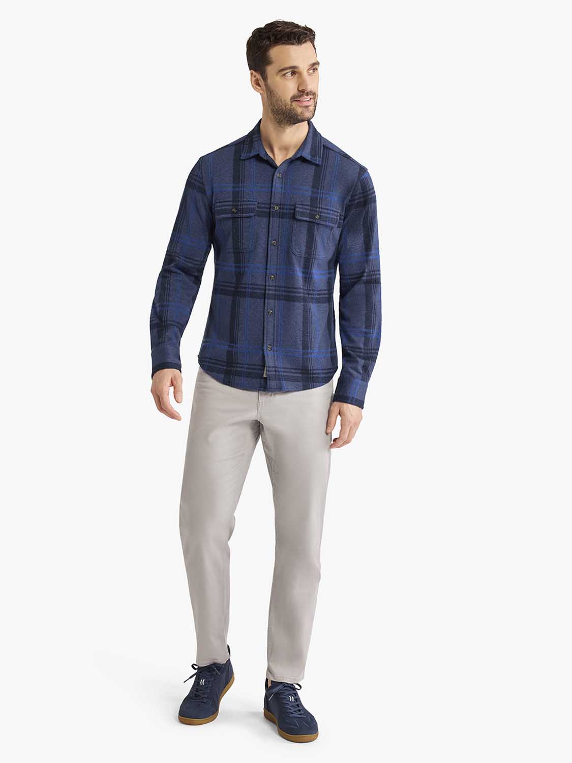 Man wearing a navy plaid flannel shirt with long sleeves and light gray pants.