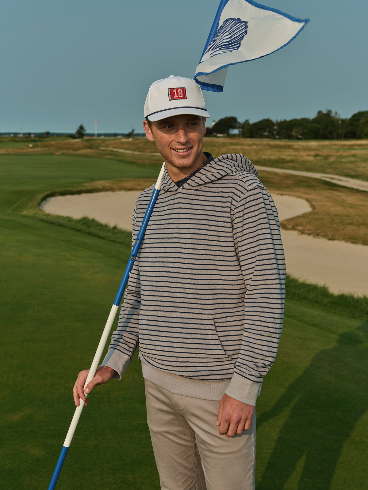 Man wearing a navy and cream striped terry hoodie on a golf course.