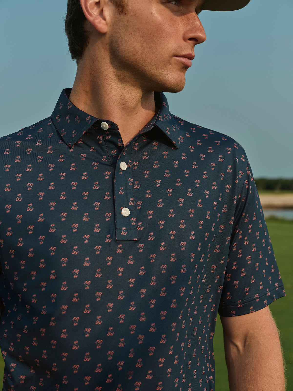 Man wearing a navy polo shirt with a small red floral pattern and white buttons.