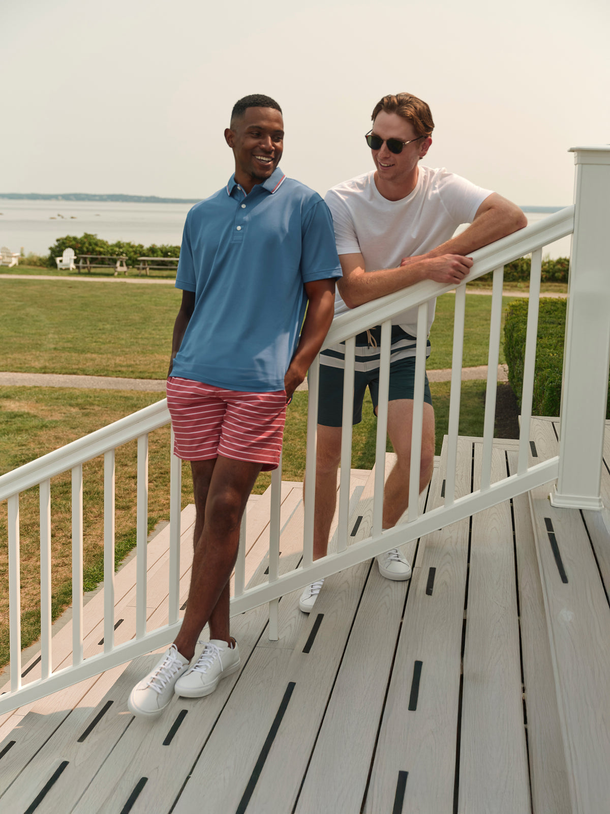 Man wearing ocean blue pique polo shirt standing on a waterfront deck with a friend.