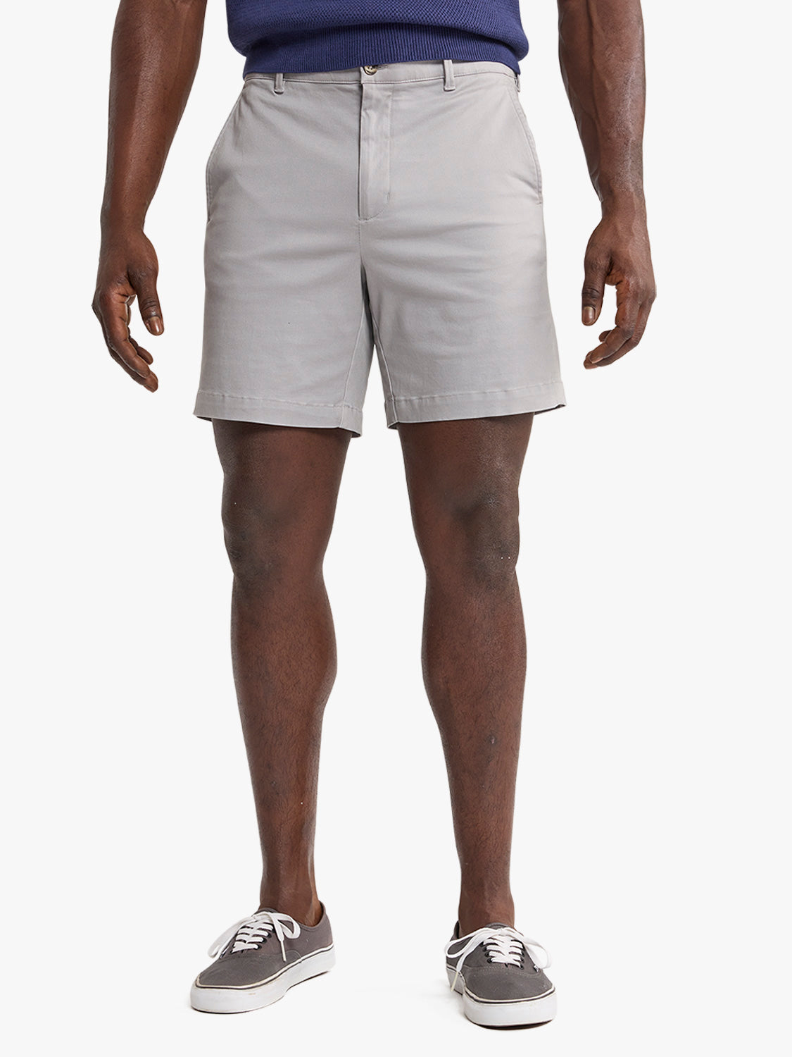 Man wearing light gray Horizon shorts with a navy sweater and gray canvas sneakers.