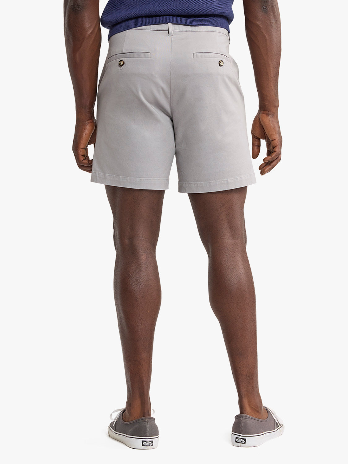 Man wearing light gray shorts with back pockets and button details, shown from behind.