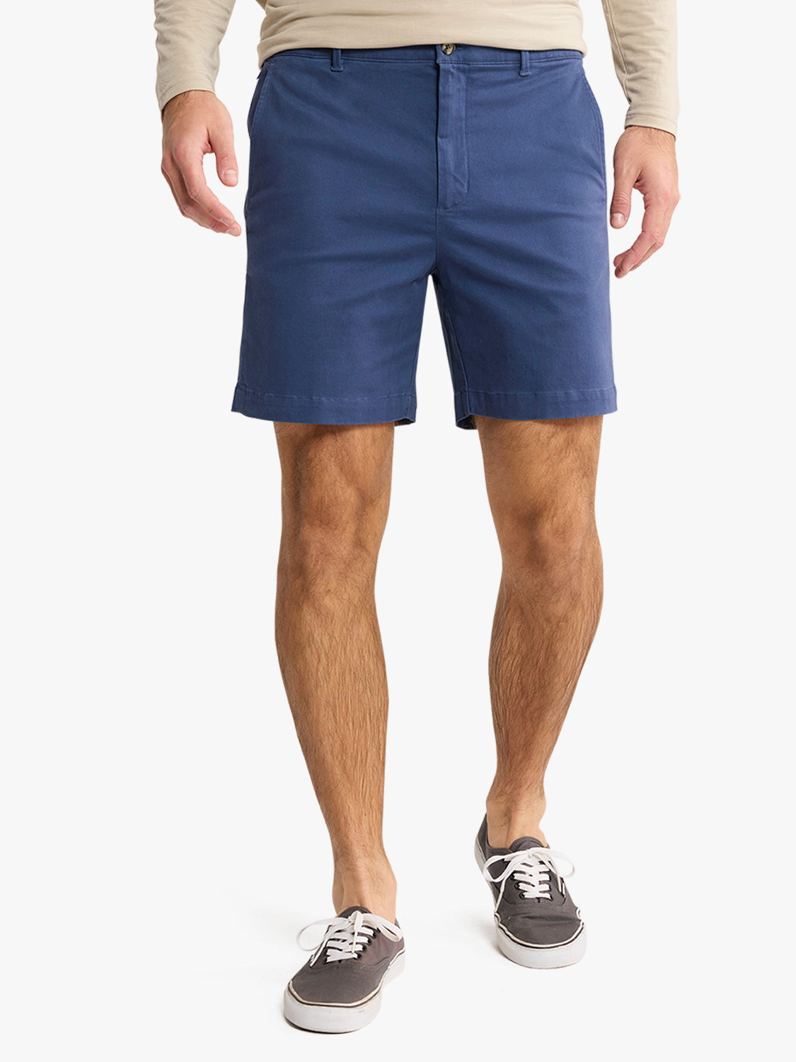 Man wearing navy blue shorts with a zipper and button fly, paired with casual sneakers.
