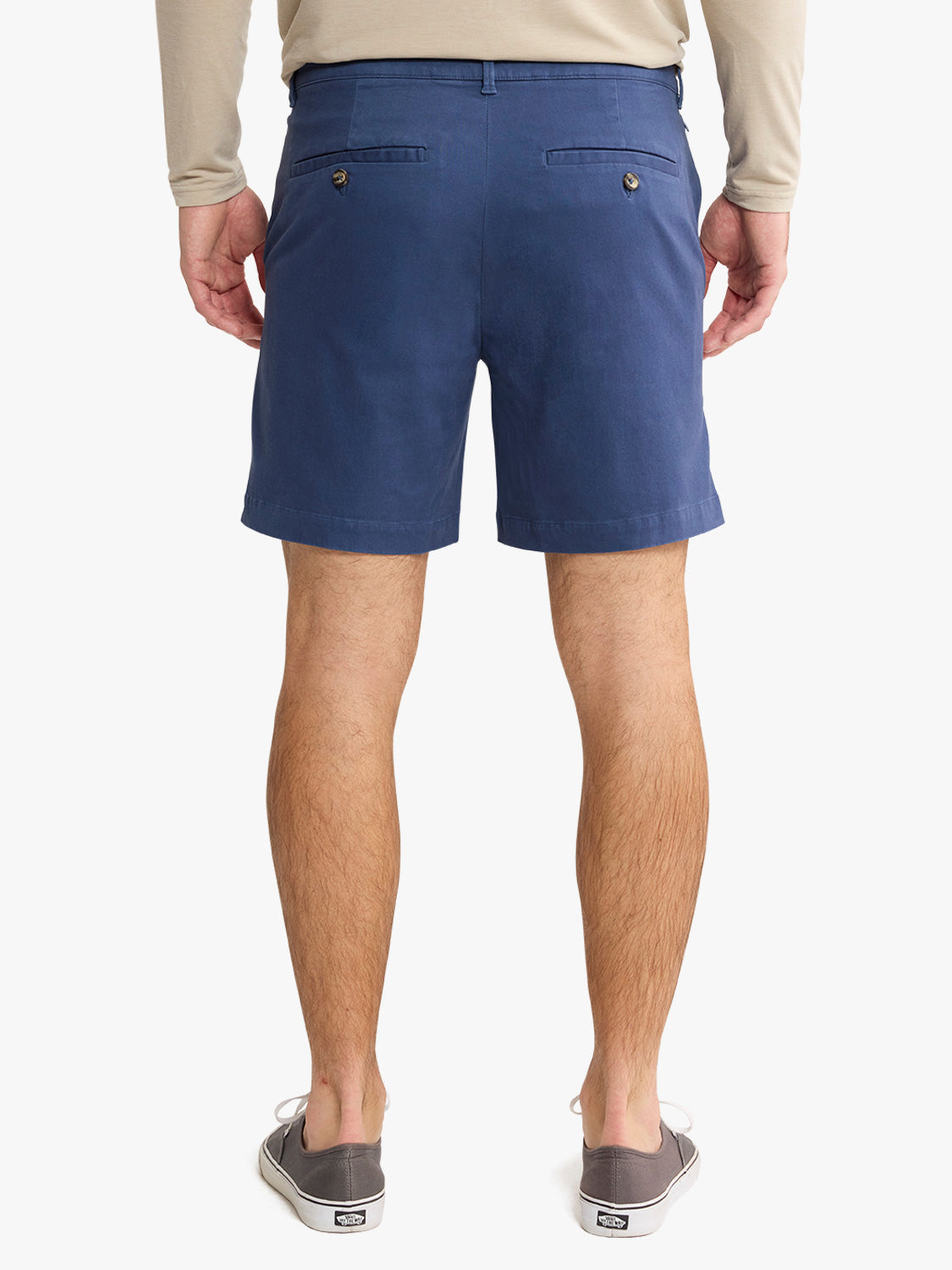 Man wearing navy blue shorts with rear pockets and button closure paired with canvas shoes.