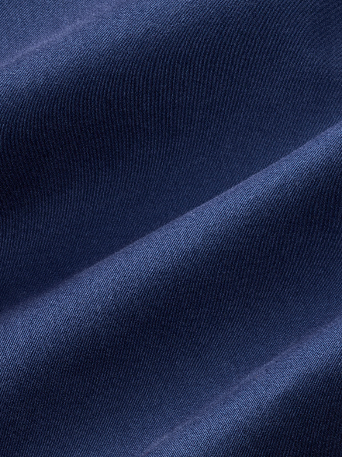 Close-up of navy ribbed fabric showing texture and diagonal folds in the material.