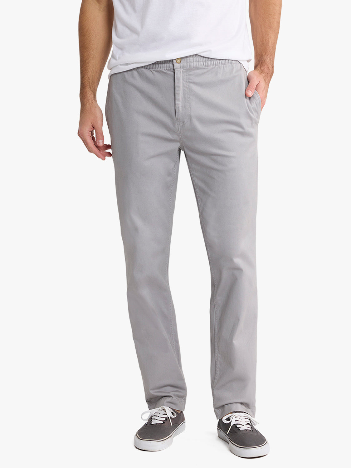 Man wearing light gray pull-on pants with a white t-shirt and dark canvas sneakers.