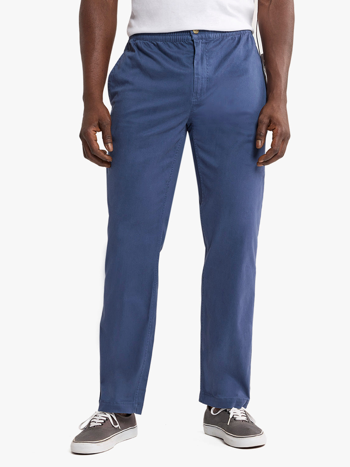 Man wearing navy pull-on pants with white shirt and gray canvas sneakers.
