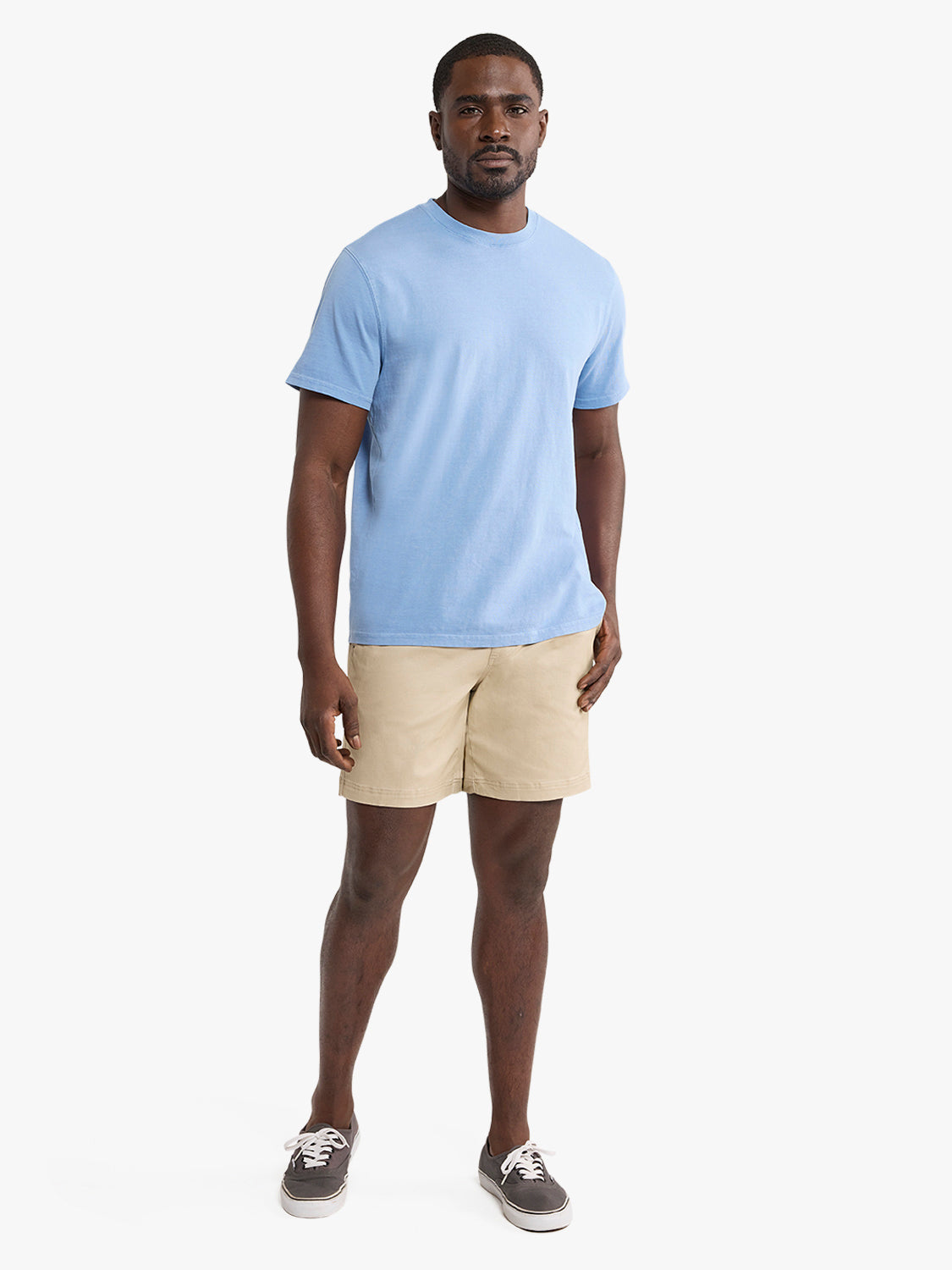 Man wearing a light blue t-shirt and khaki pull-on shorts with sneakers.
