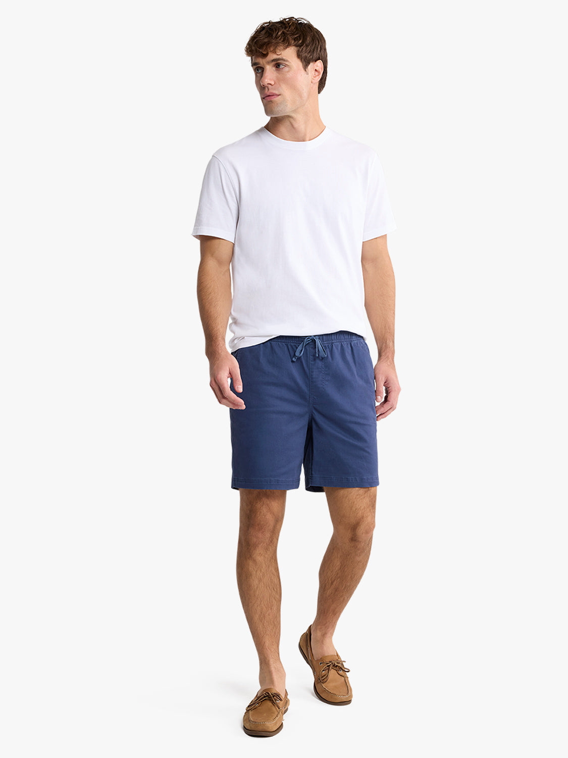 Man wearing white t-shirt and navy pull-on shorts with drawstring waist and boat shoes.