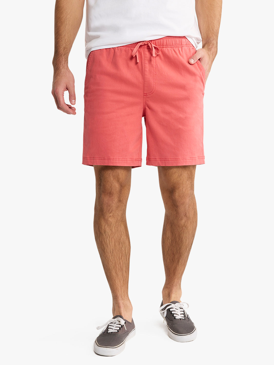 Man wearing washed red pull-on shorts with drawstring waist and white sneakers.
