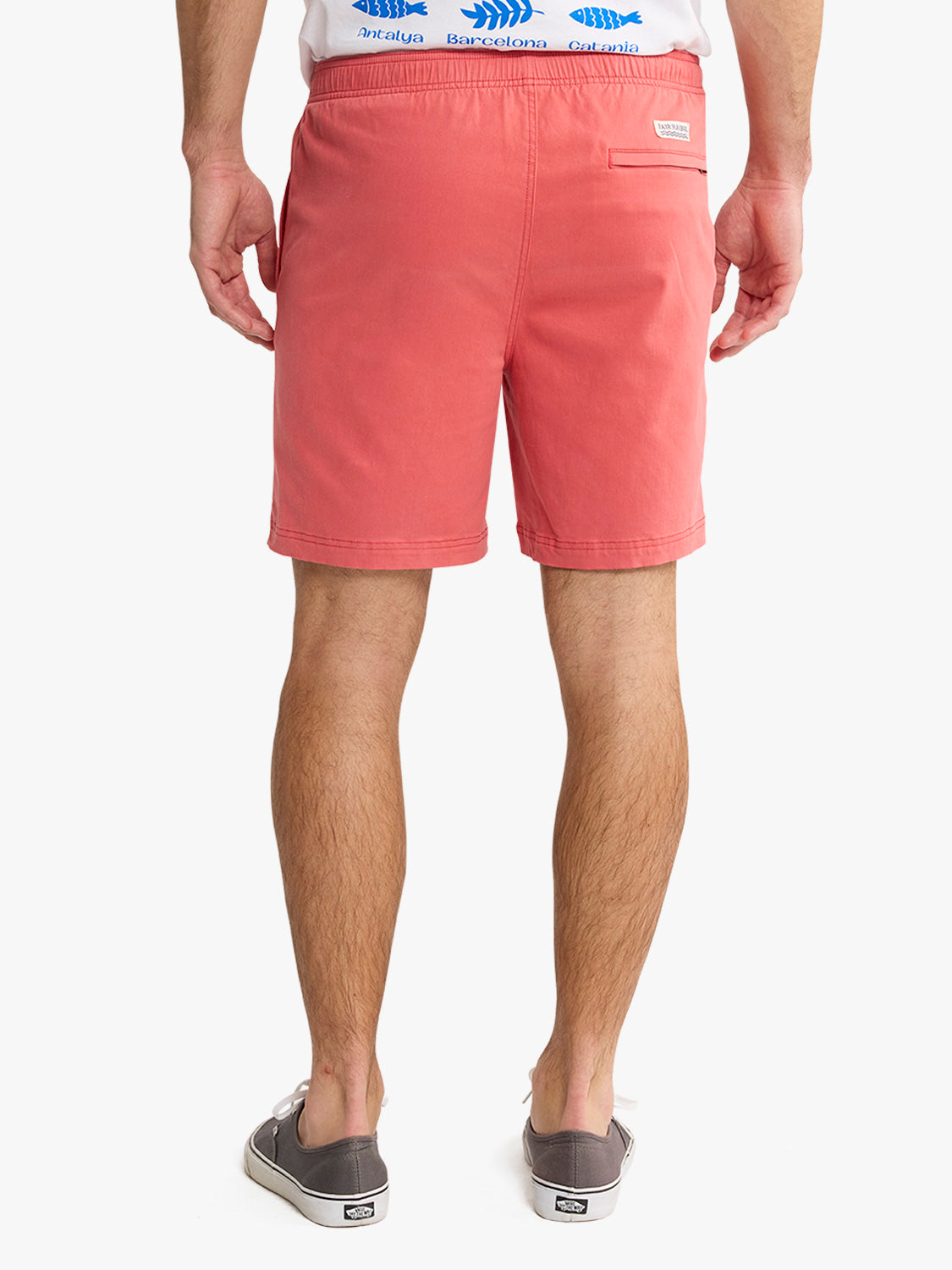 Man wearing washed red pull-on shorts with elastic waistband and back pocket detail.
