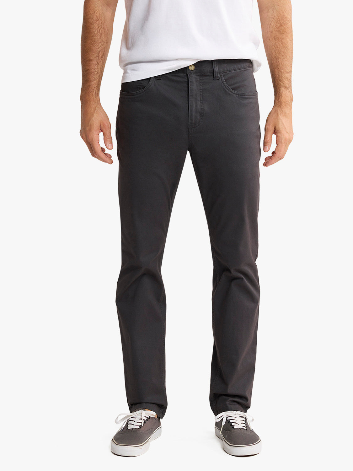 Man wearing black five-pocket pants with white t-shirt and gray canvas sneakers.