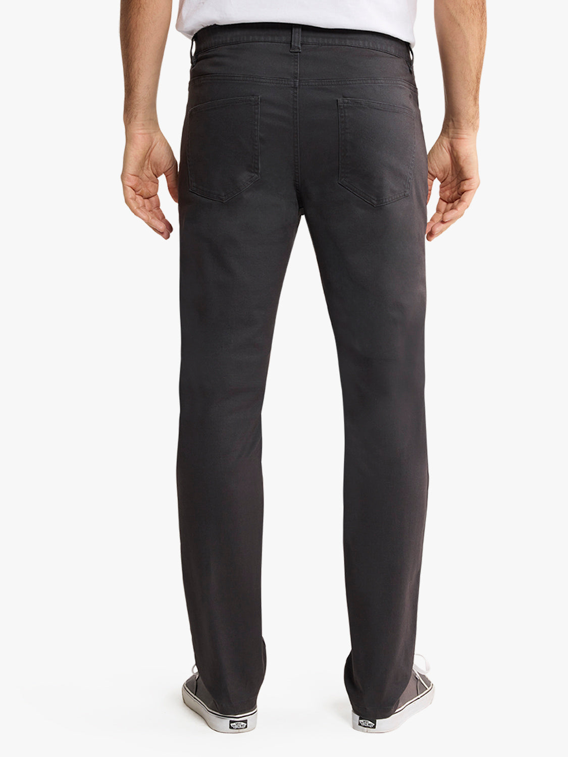 Man wearing black five-pocket pants with white shirt, viewed from back.