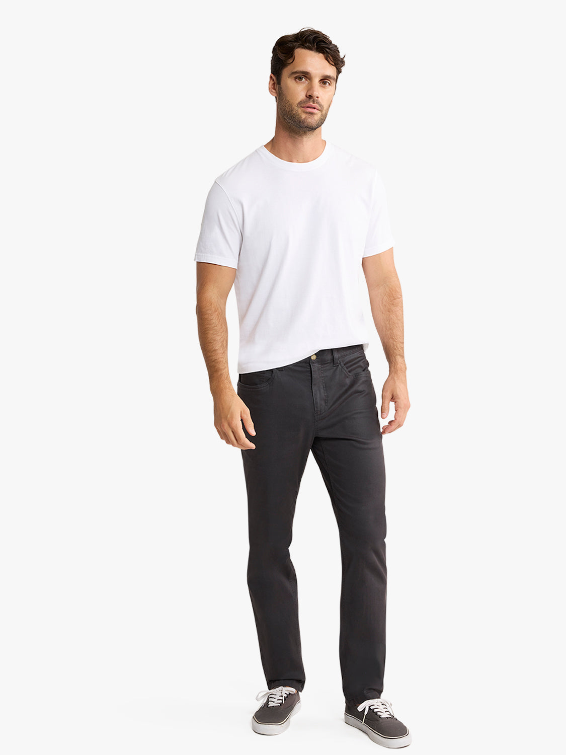 Man wearing a white t-shirt and black five-pocket pants styled with gray sneakers.