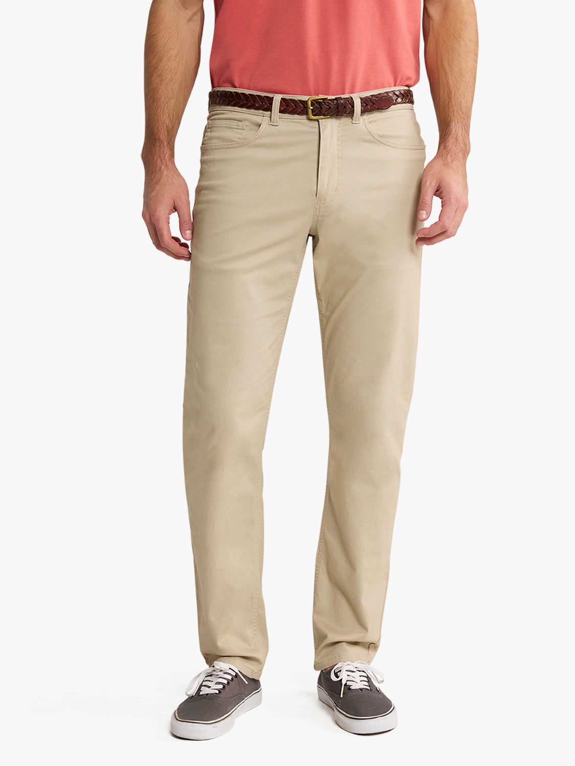 Man wearing khaki five-pocket pants with a patterned belt and casual sneakers.